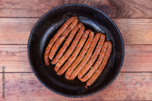 Top view of baked pork sausages on cast frying pan