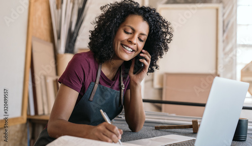 Smiling entrepreneur talking on the phone in her framing studio photo