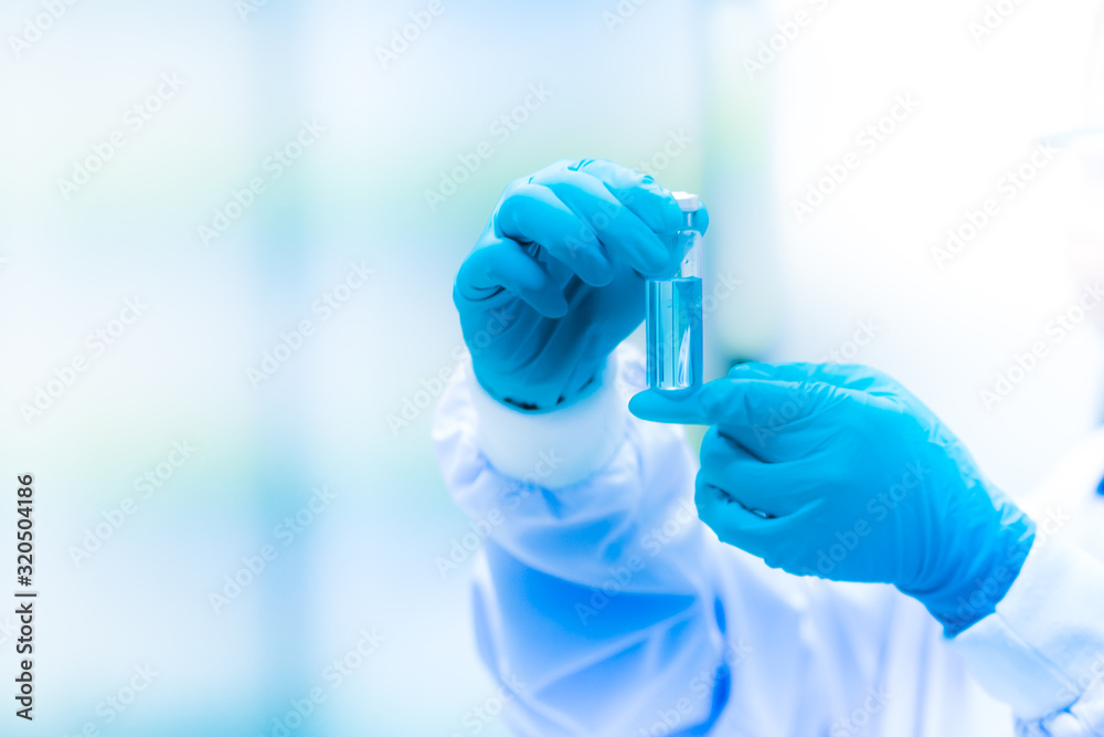 hands of scientists wearing blue rubber gloves experimented with glass bottles containing various chemicals in the research and development concepts in science laboratories, shallow focus effect hands of scientists wearing blue rubber gloves experimented with glass bottles containing various chemicals in the research and development concepts in science laboratories, shallow focus effect