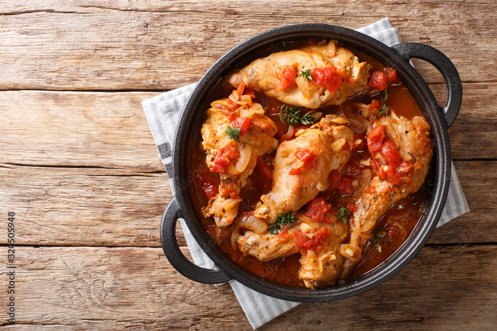 Tasty spicy rabbit stew in tomato sauce with white wine and herbs close-up in a pan. Horizontal top view Tasty spicy rabbit stew in tomato sauce with white wine and herbs close-up in a pan. Horizontal top view