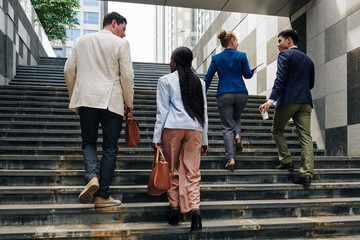 Business people walking up the stairs when going to work in the morning, view from the back