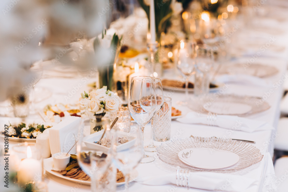 Fototapeta premium formal luxury elegant wedding decor restaurant tables served white tablecloth, plates, menus, glasses, tulips in vases, orchids, candles silver chairs, blue background