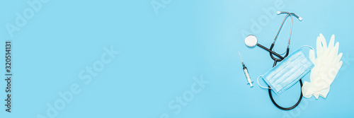 Medical stethoscope, latex gloves, syringe and protective mask on a blue background. Concept medicine, nurse, hospital, safety, epidemic. Banner. Flat lay, top view