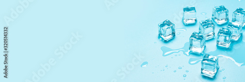 Ice cubes with water on a blue background. Ice concept for drinks. Banner. Flat lay, top view photo