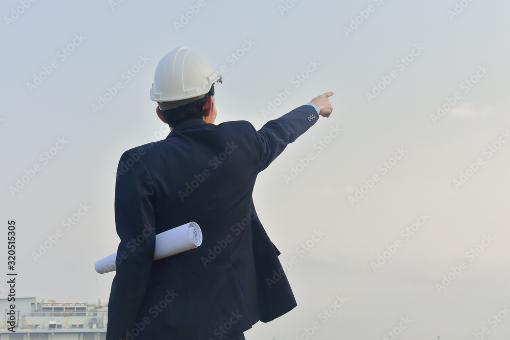 Businessman holding blueprint standing outdoors at construction site Businessman holding blueprint standing outdoors at construction site