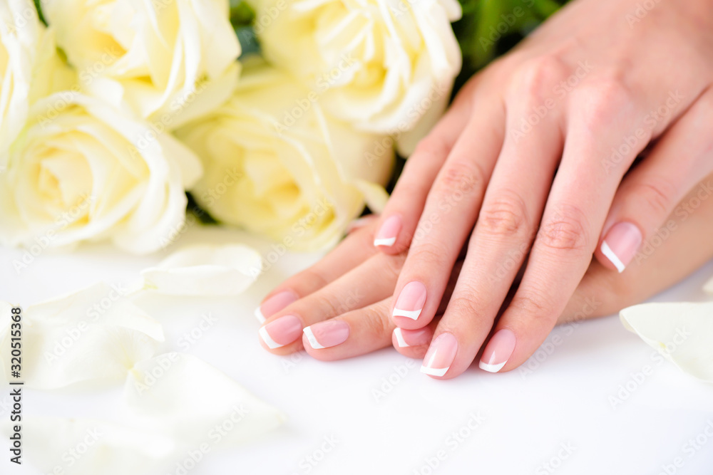 Hands of a woman with beautiful french manicure and white roses