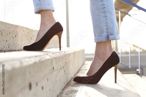 Fototapeta Profile of woman legs wearing high heels walking up stairs