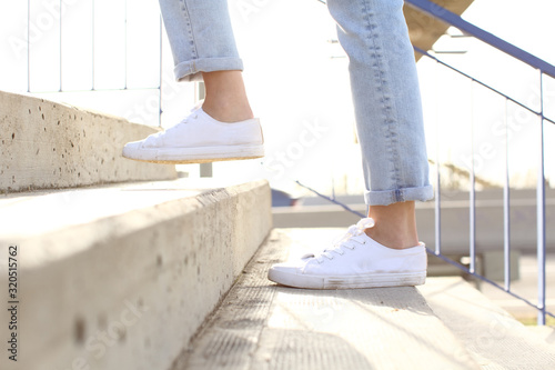 Profile of woman legs wearing sneakers walking up stairs photo