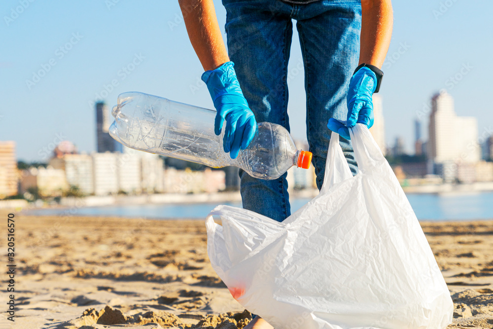 Clean beach from plastic. Volunteer hands picking up plastic bottle trash  from the beach and putting into plastic bag for recycle Stock Photo | Adobe  Stock