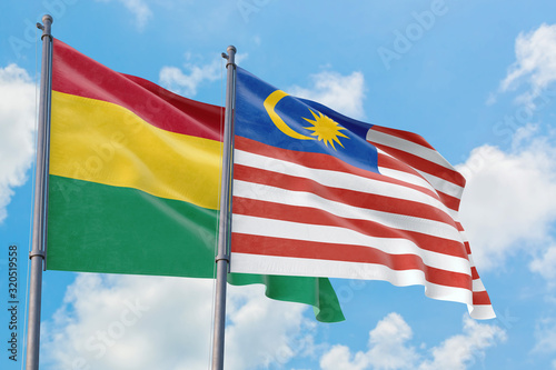 Malaysia and Bolivia flags waving in the wind against white cloudy blue sky together. Diplomacy concept  international relations.