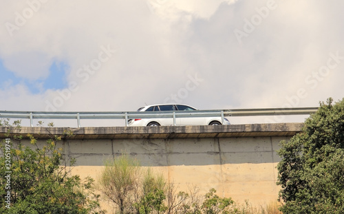 A car on the overpass that fenced by shoulder