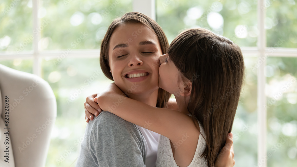 Loving little girl hug and kiss young mother Loving little girl hug and kiss young mother