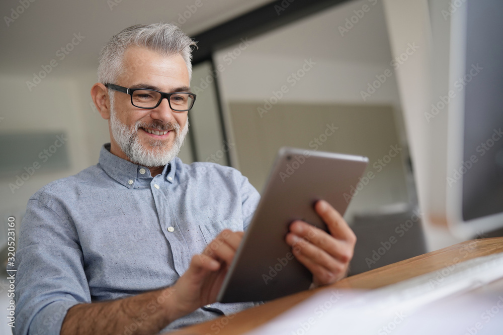 Mature man in office working with digital tablet Mature man in office working with digital tablet