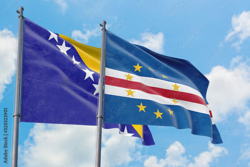 Cape Verde and Bosnia Herzegovina flags waving in the wind against white cloudy blue sky together. Diplomacy concept, international relations. Cape Verde and Bosnia Herzegovina flags waving in the wind against white cloudy blue sky together. Diplomacy concept, international relations.