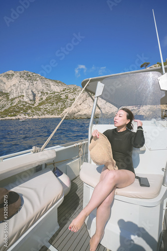 Marseille, France - August 13th, 2019:A young woman is enjoying sunshine and beautiful view in Calanques de Morgiou, Marseilles, Provence, South of France.  She looks very cheerful and happy.