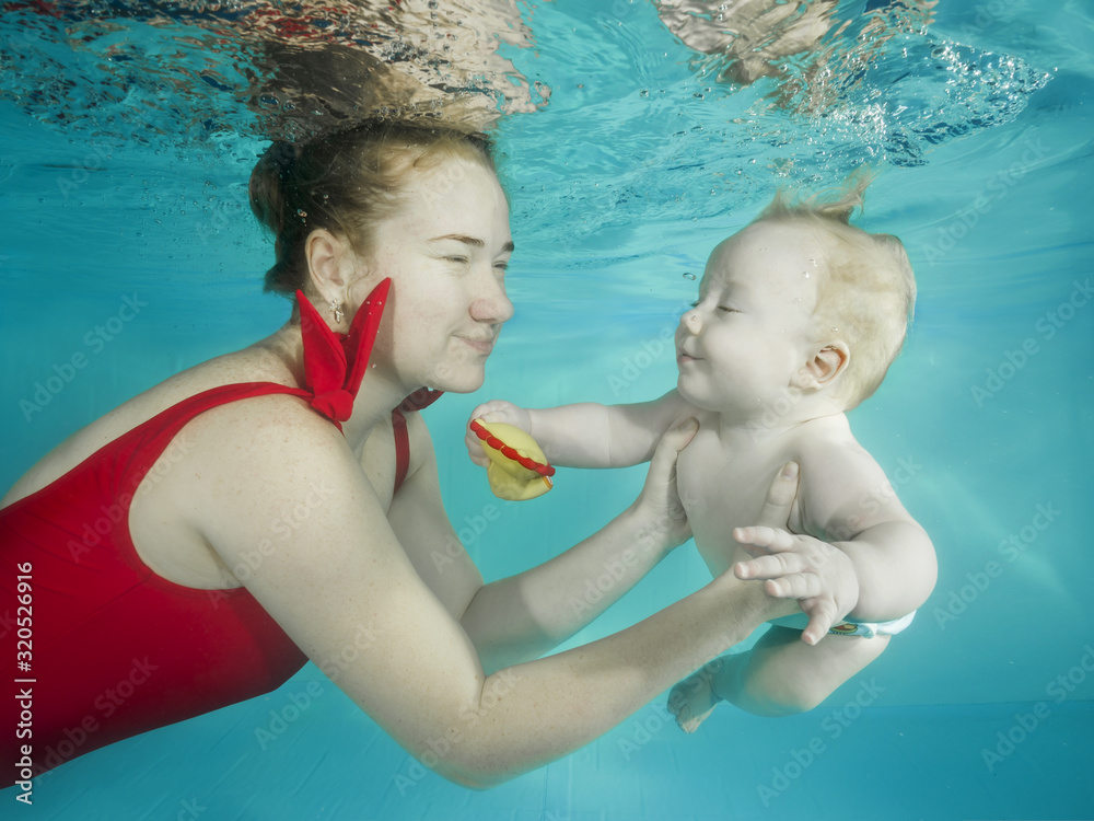 Mom with a little son dives underwater in a swimming pool