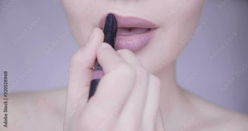 Close up portrait of young woman applying lipstick wearing nose ring piercing Close up portrait of young woman applying lipstick wearing nose ring piercing