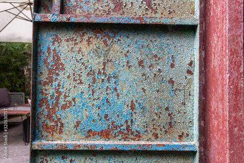 old metal background door with peeling decayed blue paint