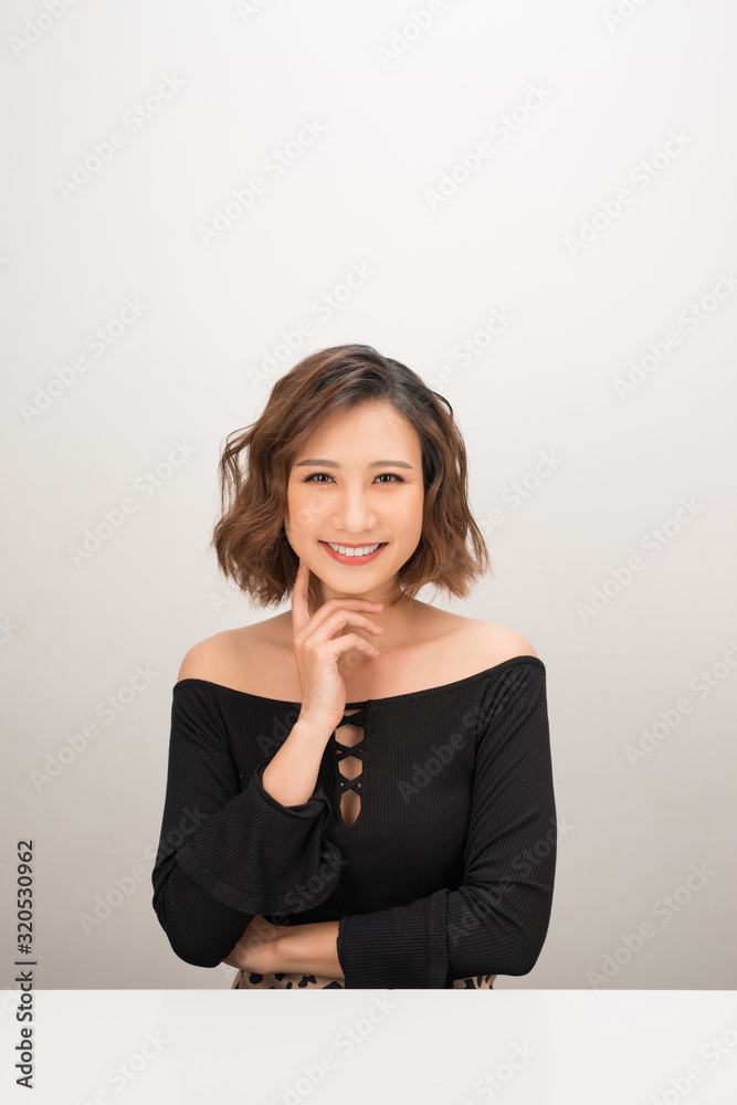 Portrait of a cheerful Asian businesswoman sitting at the table on white background Portrait of a cheerful Asian businesswoman sitting at the table on white background
