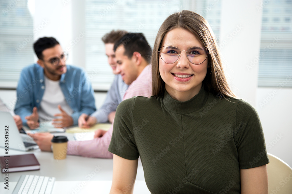 Portrait of a young business woman on a background of her colleagues working in the office Portrait of a young business woman on a background of her colleagues working in the office