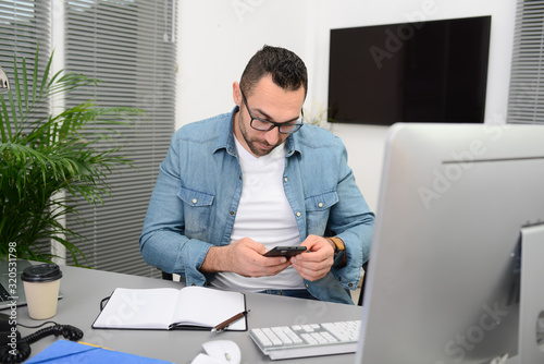 handsome young happy and successful businessman in casual wear at office business desk