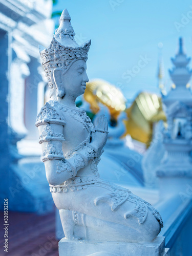 White stupas and a golden reclining buddha surrounded by white sculptures. Wat Pong Sunan Temple in the city of Prae in northern Thailand. photo