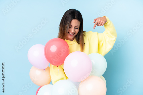 Woman holding balloons in a party over isolated blue background