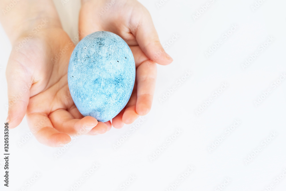 Children's hands are holding an Easter egg. Beautiful egg painted for Easter. Close up of a blue egg Children's hands are holding an Easter egg. Beautiful egg painted for Easter. Close up of a blue egg