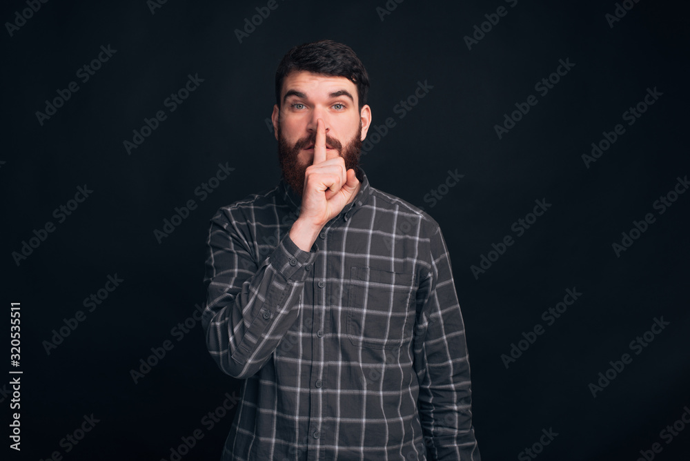 It's a secret, don't tell to anybody. Handsome bearded guy is making shut up gesture. It's a secret, don't tell to anybody. Handsome bearded guy is making shut up gesture.