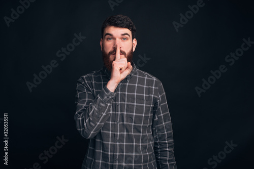 It s a secret  don t tell to anybody. Handsome bearded guy is making shut up gesture.