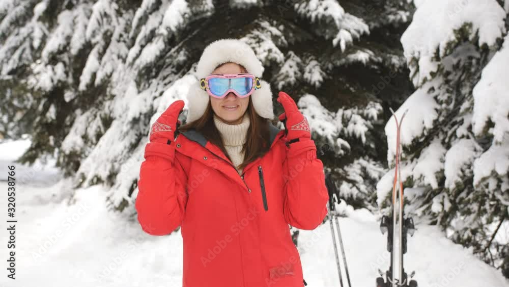 Happy woman wearing ski goggles in the ski resort and goes skiing. Happy woman wearing ski goggles in the ski resort and goes skiing.
