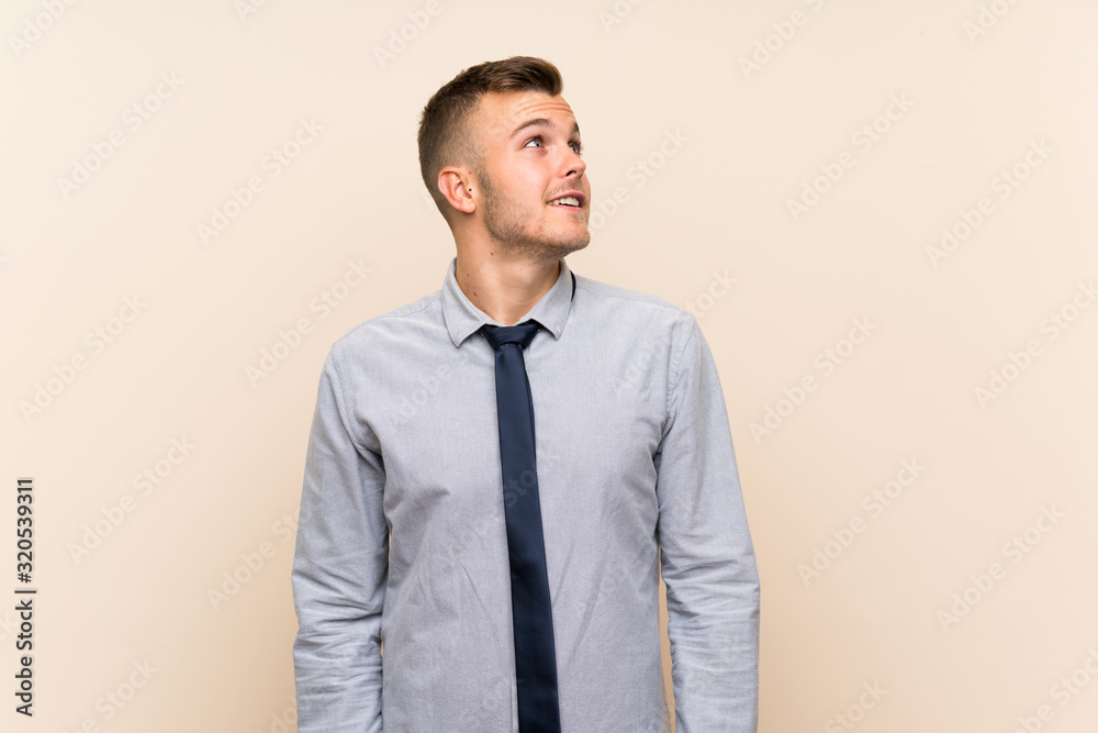 Young blonde businessman over isolated background laughing and looking up Young blonde businessman over isolated background laughing and looking up
