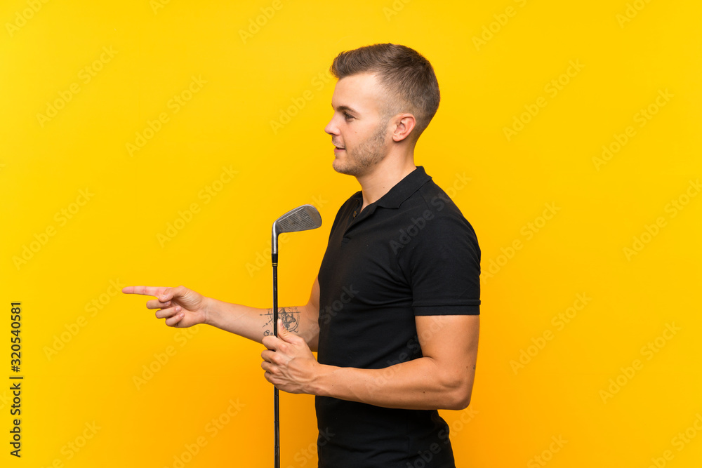 Golfer player man over isolated yellow background pointing to the side to present a product Golfer player man over isolated yellow background pointing to the side to present a product