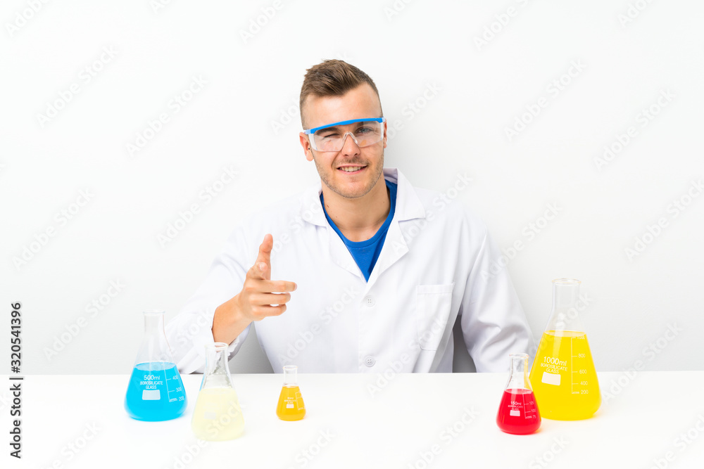 Young scientific with lots of laboratory flask points finger at you Young scientific with lots of laboratory flask points finger at you