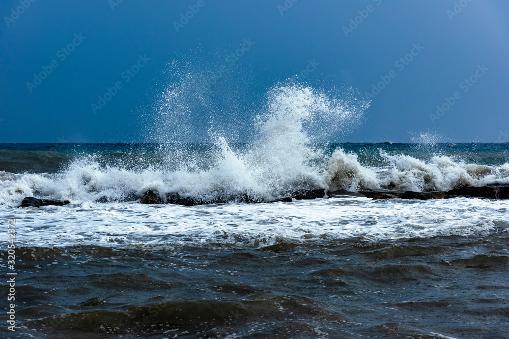View of a storm at sea with high white waves of wild splashing water, and a dark threatening sky. View of a storm at sea with high white waves of wild splashing water, and a dark threatening sky.