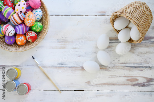 Painting eggs for easter holiday celebration on white wooden background