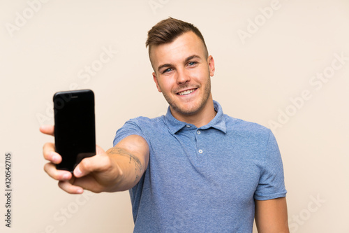 Young blonde man using mobile phone with happy expression