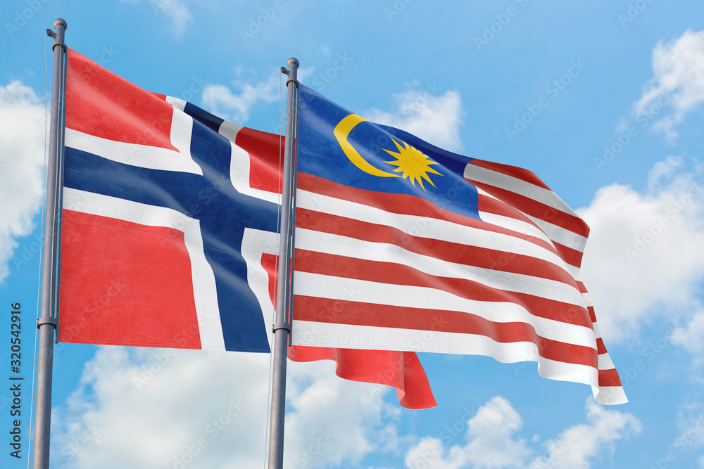 Malaysia and Bouvet Islands flags waving in the wind against white cloudy blue sky together. Diplomacy concept, international relations.