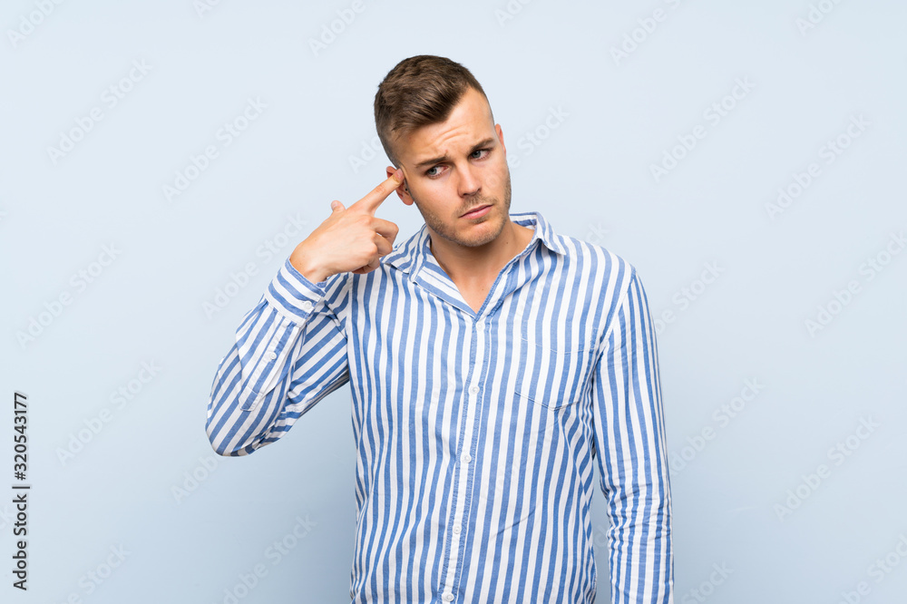 Young handsome blonde man over isolated blue background making the gesture of madness putting finger on the head Young handsome blonde man over isolated blue background making the gesture of madness putting finger on the head