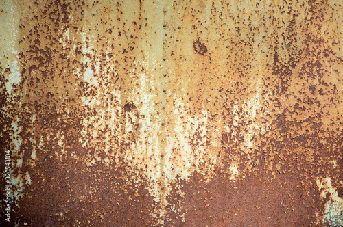 Cracked green paint peeling off rusty metal sheet panel. Brown weathered grunge texture.