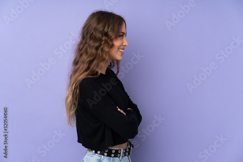 Young woman over isolated purple background in lateral position