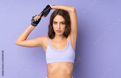 Fototapeta Naklejka Na Ścianę i Meble -  Young sport woman over isolated purple background stretching