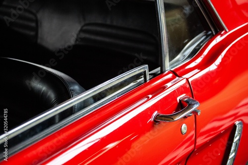 open window and door handle of red classic car