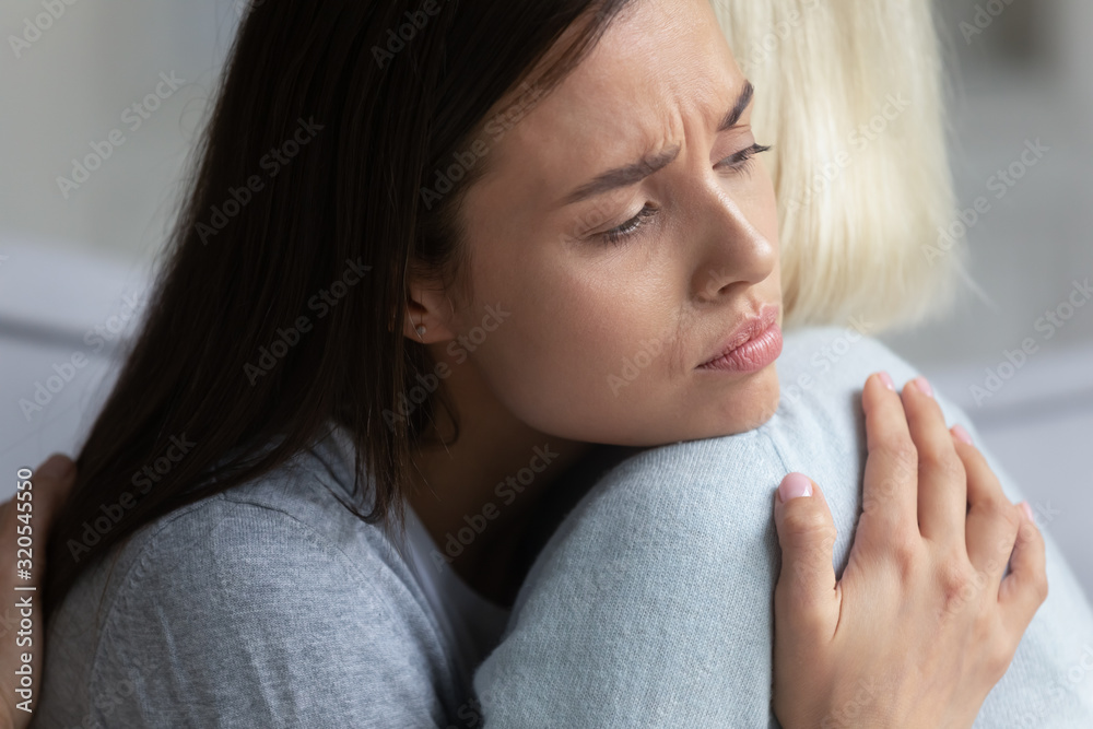 Upset mom and adult daughter hug showing support and care