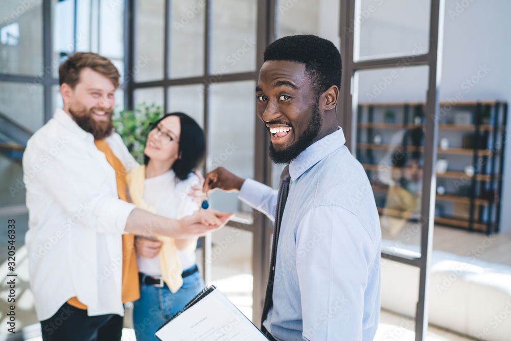 Ethnic estate agent giving apartment key to couple Ethnic estate agent giving apartment key to couple