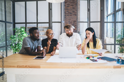 Group of disappointed multiethnic coworkers using laptop at office photo