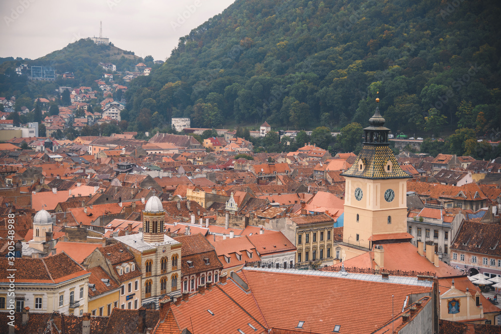 Brasov, Romania - 10/04/2017: orange roofs and clock tower in old city.