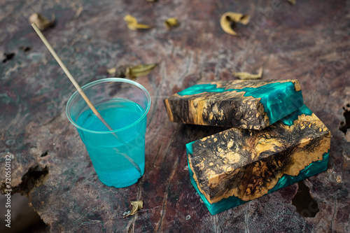 Casting blue epoxy resin burl wood cube on old table art background photo