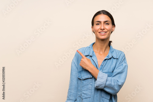 Young woman over isolated background pointing to the side to present a product