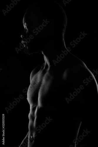 black and white portrait of a handsome black man with naked sports torso on dark background